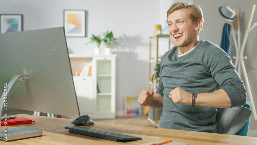 Portrait of the Handsome Young Man Dances while Sitting Before His Computer. Young Man Having Fun at Home. Portrait of the Handsome Young Man Dances while Sitting Before His Computer. Young Man Having Fun at Home.
