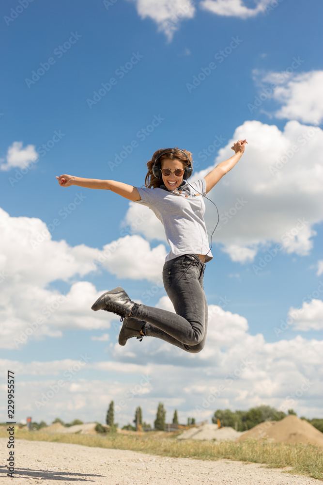 Beautiful young woman jumping in the air with headphones Beautiful young woman jumping in the air with headphones