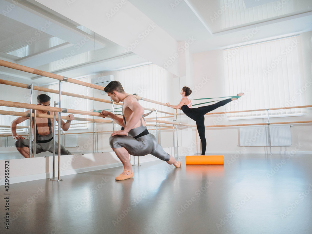 Preparation of body before performance in ballet studio. Male dancer and ballerina warming up near barre on rehearsal Preparation of body before performance in ballet studio. Male dancer and ballerina warming up near barre on rehearsal