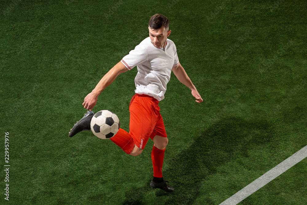Football player tackling for ball over green grass background. Professional football soccer player in motion at studio. Fit jumping man in action, jump, movement at game. Football player tackling for ball over green grass background. Professional football soccer player in motion at studio. Fit jumping man in action, jump, movement at game.
