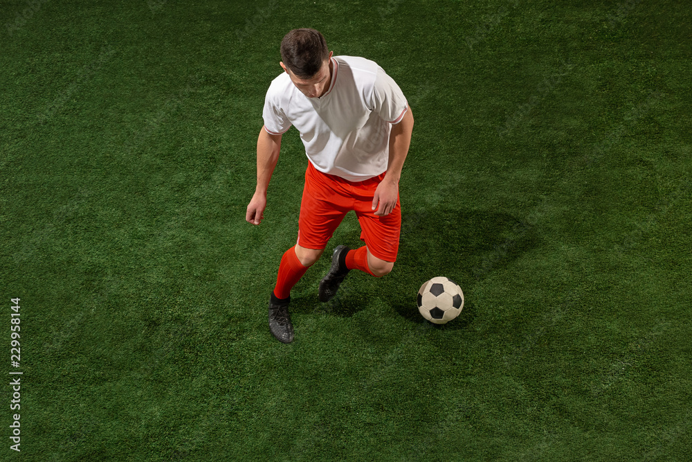 Football player tackling for ball over green grass background. Professional football soccer player in motion at studio. Fit jumping man in action, jump, movement at game. Football player tackling for ball over green grass background. Professional football soccer player in motion at studio. Fit jumping man in action, jump, movement at game.