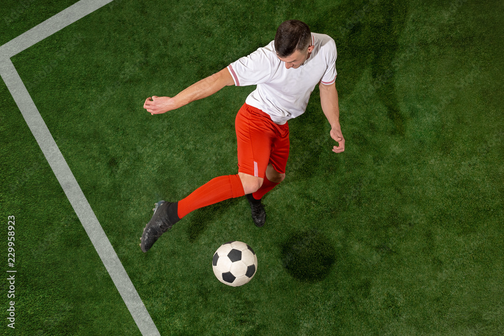 Football player tackling for ball over green grass background. Professional football soccer player in motion at studio. Fit jumping man in action, jump, movement at game. Football player tackling for ball over green grass background. Professional football soccer player in motion at studio. Fit jumping man in action, jump, movement at game.