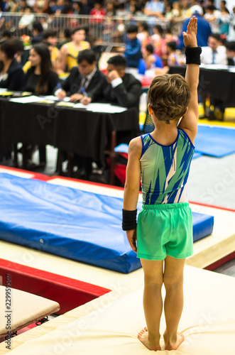 Portrait of a gymnast child waving to the jury after competing