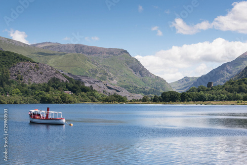 A boat on the tranquil blue waters of Llyn padarn, a naturally formed lake in Snowdonia, north Wales © annapimages
