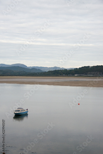 A small blue boat in a bay art low tide, North Wales