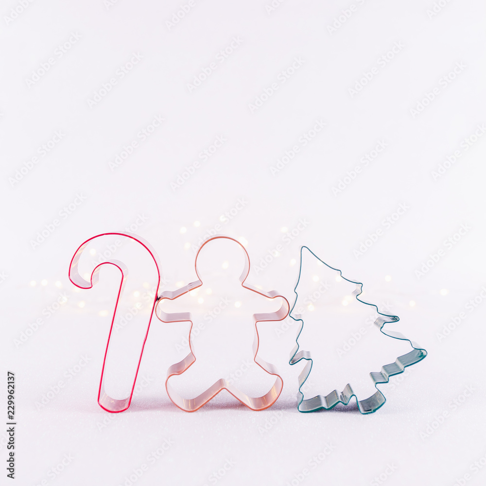 Obraz premium Multicolor cookie cutters on white sparkling background with bokeh lights. Holiday Christmas and New Year background