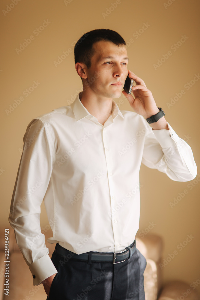 Handsome man in shirt on his wedding day. He stand hear the window Handsome man in shirt on his wedding day. He stand hear the window