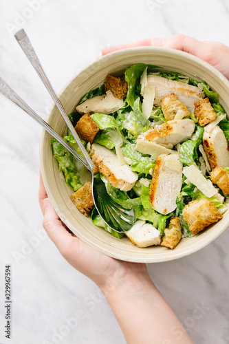 Woman holding bowl of chicken caesar salad