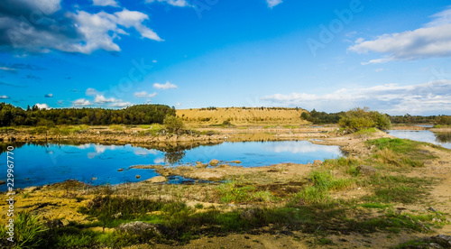 Sandy hills. Lake in the Sandy canyon. Warm colors background. Yellow sandstone textured mountain, white thin sand dune, bright sky. Sunshine landscape