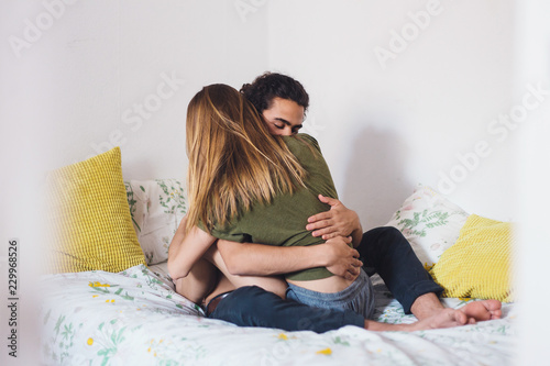Young heterosexual couple hugging in bed