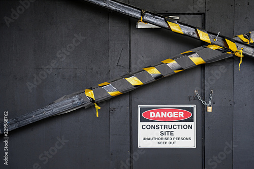 Close up of do not enter construction zone and danger sign on black wall with tape