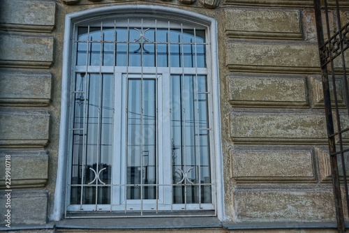 window behind steel grate on gray concrete wall