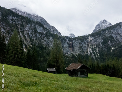 Green meadow, wooden cabin, cliff with waterfall, summit and clouds