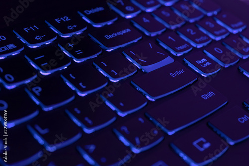 Blue backlit laptop keyboard, hacking and blockchain concept