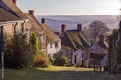 Famous view of Gold Hill in Shaftesbury village, Dorset, England, UK, with beautiful countryside in the background photo