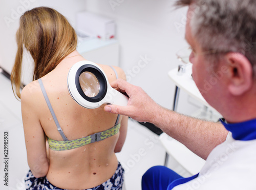 Prevention of melanoma. The doctor examines birthmarks or other benign neoplasms of the patient with a special electronic magnifier.