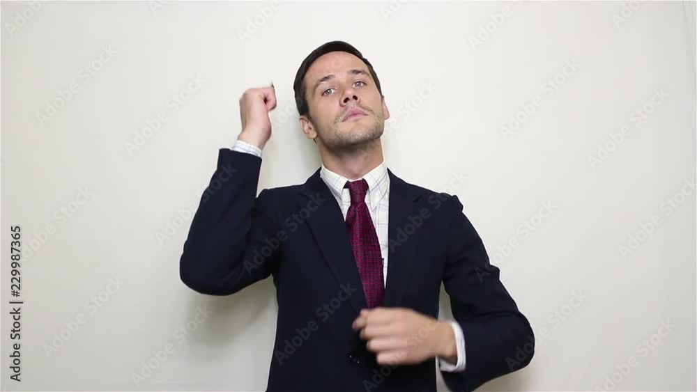 Young handsome businessman in a blue suit combing her hair and adjusts his suit, looking at the camera.Portrait on a white background. Young handsome businessman in a blue suit combing her hair and adjusts his suit, looking at the camera.Portrait on a white background.
