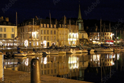 Honfleur, France - July 10 2017: Honfleur harbour in Normandy by night, France. Color houses and their reflection in water