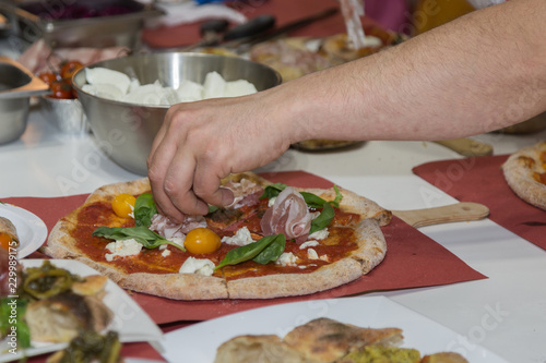 Pizza Maker who Prepares a Delicious Pizza with Bacon and Cherry Tomatoes