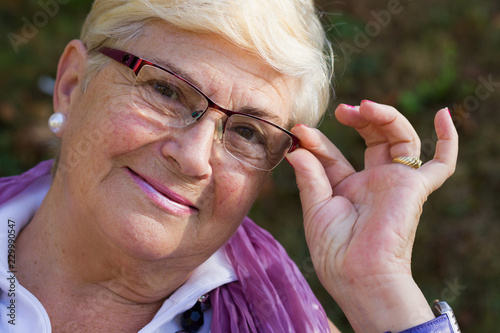 Принти на полотні Closeup of smiling senior woman holding eyeglasses