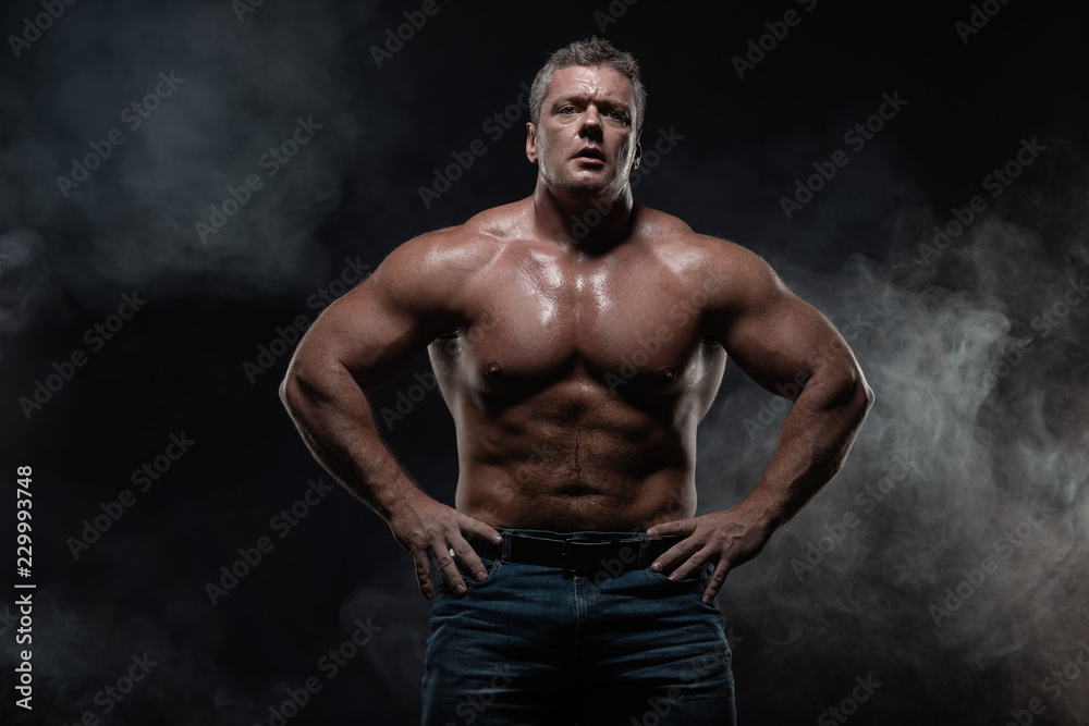 Powerful muscular bodybuilder posing on a black background. concept of strength and health Powerful muscular bodybuilder posing on a black background. concept of strength and health