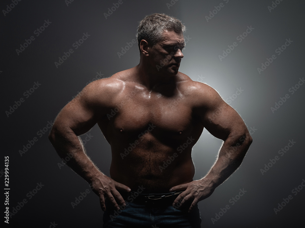 Fototapeta premium Powerful muscular bodybuilder posing on a black background. concept of strength and health