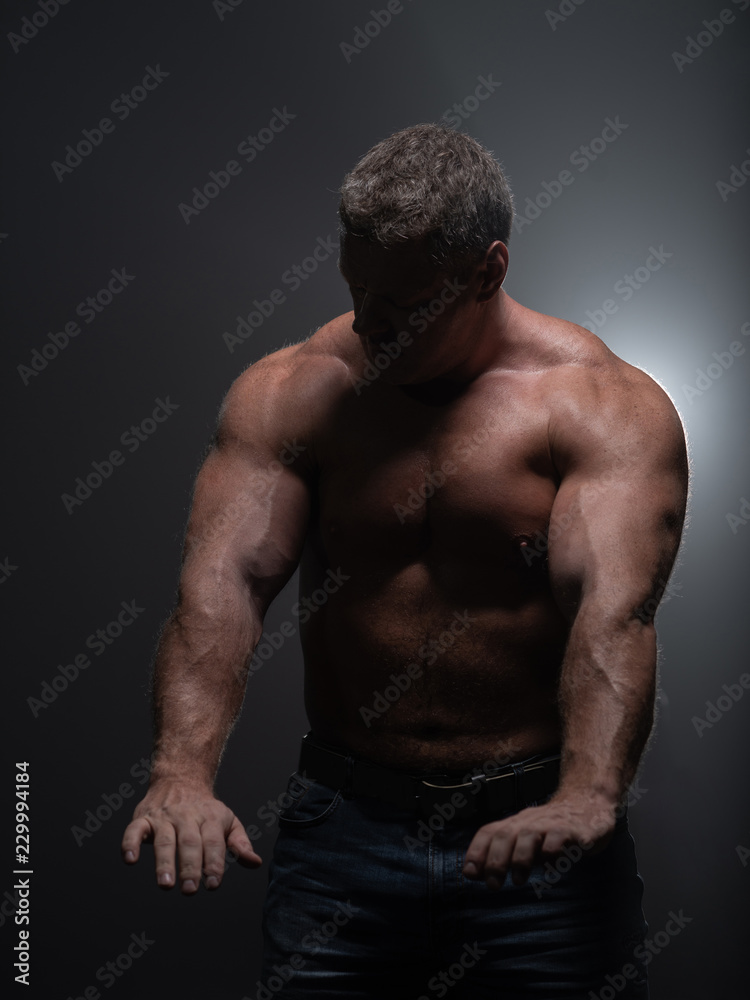 Fototapeta premium Powerful muscular bodybuilder posing on a black background. concept of strength and health
