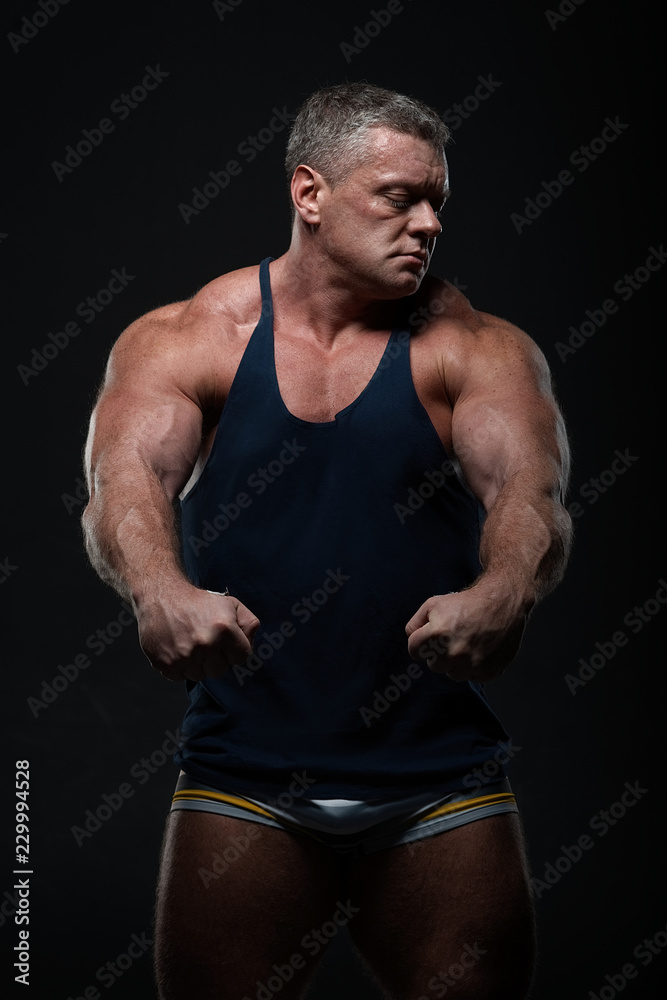Fototapeta premium Powerful muscular bodybuilder posing on a black background. concept of strength and health