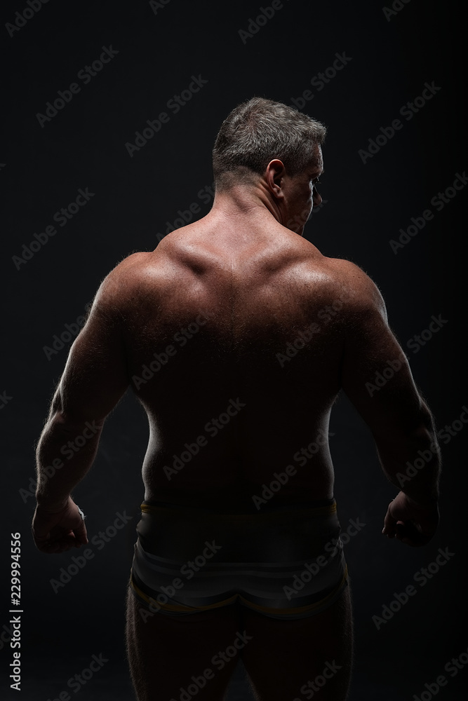 Muscular man with a powerful back posing on a black background. concept of sports and fitness