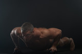 muscular man does pushups in the smoke on a black background