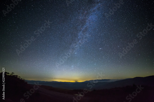 Sky with first stars and clouds during sunset. The road is illuminated by the light of the milky way. Photographed in the Caucasus, Russia. © olgapkurguzova
