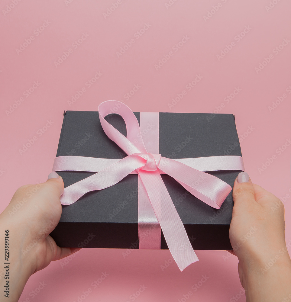 Female hands give gift box. Female manicured hands give gift box with pink bow. Holiday and celebration concept - obrazy, fototapety, plakaty 