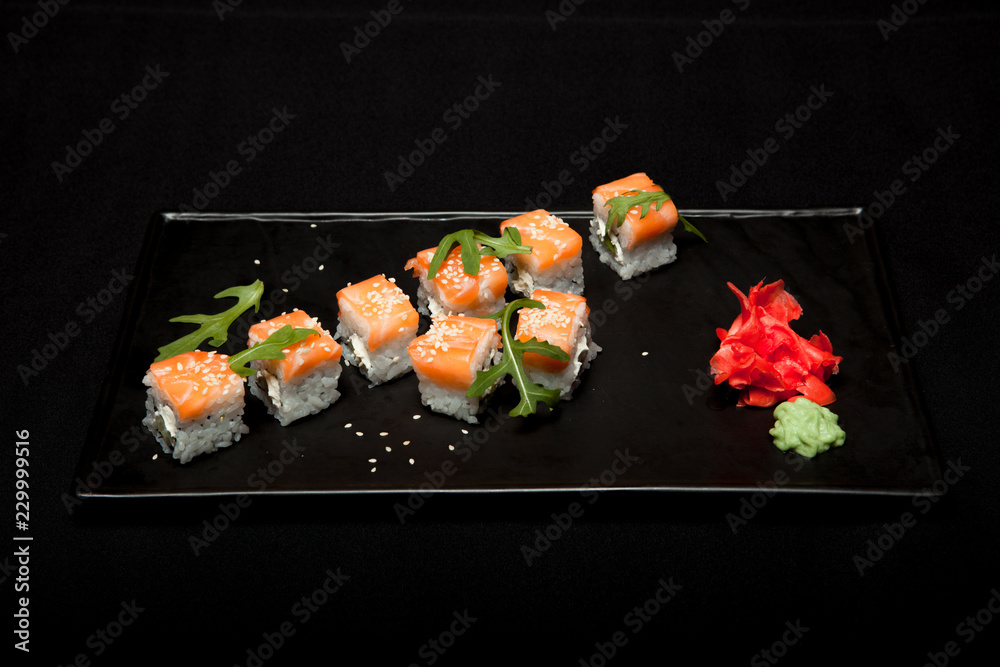 Sushi roll with salmon and avocado on plate on black background top view Sushi roll with salmon and avocado on plate on black background top view