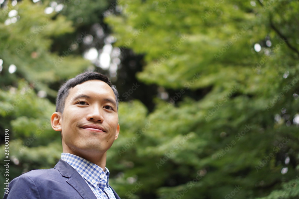 Portrait of a southeast asian young man smiling in a park Portrait of a southeast asian young man smiling in a park