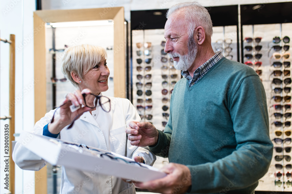 Handsome senior man choosing eyeglasses frame in optical store. Handsome senior man choosing eyeglasses frame in optical store.