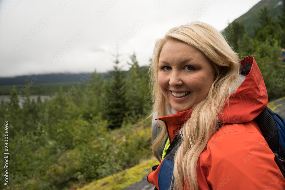 Female hiker wearing a rain jacket enjoys the views in Seward Alaska in the wilderness of Kenai Fjords National Park