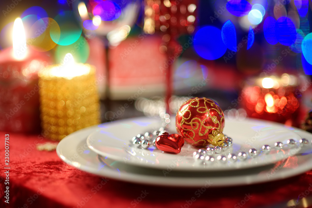 Beautiful table setting for Christmas party or New Year celebration at home. Cozy room with a fireplace and Christmas tree in a background.