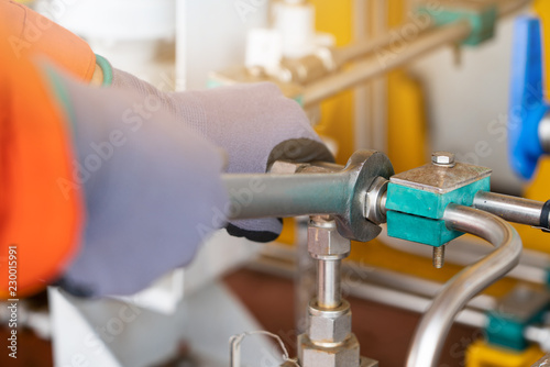 A mechanic operator fix and tighten stainless steel tubing system by using combination wrench, offshore oil and gas industry maintenance and service business