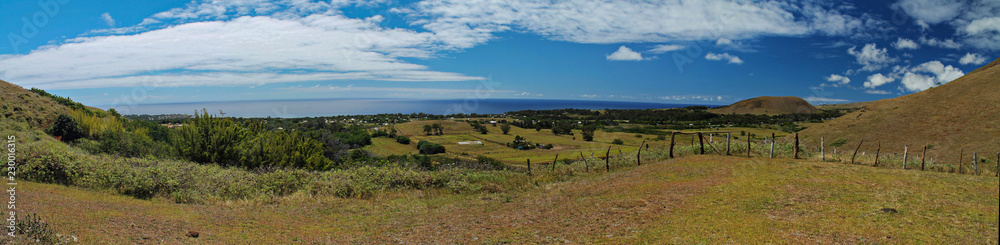 Vista panorâmica de uma estrada de terra deserta atravessando um campo com montanhas ao fundo, na Ilha de Páscoa, em um dia ensolarado com céu azul e nuvens, destacando a paisagem natural. Vista panorâmica de uma estrada de terra deserta atravessando um campo com montanhas ao fundo, na Ilha de Páscoa, em um dia ensolarado com céu azul e nuvens, destacando a paisagem natural.