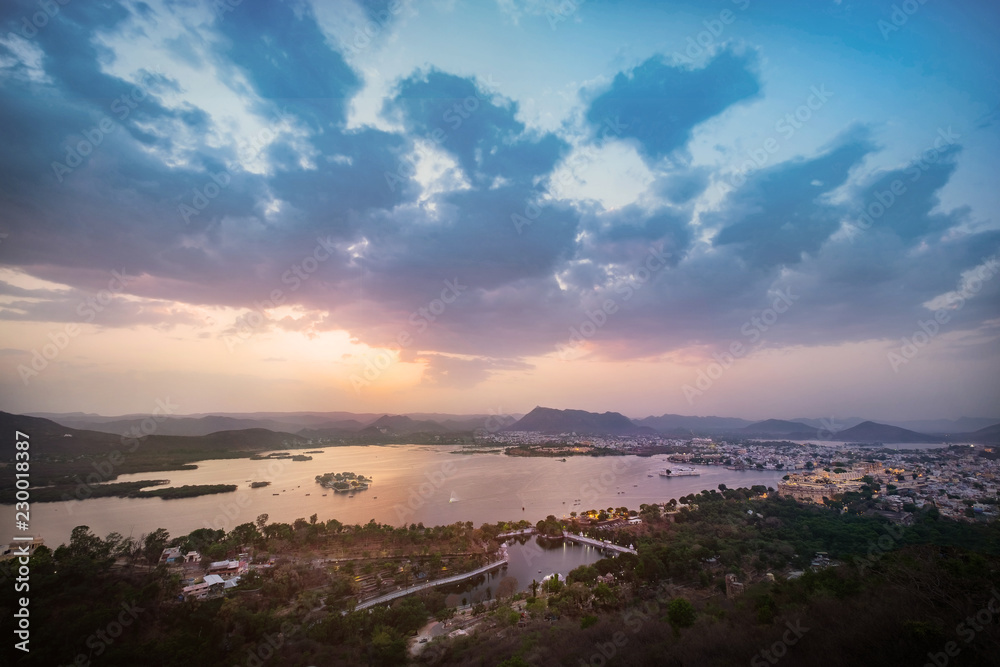 Sunset at Udaipur city at lake Pichola in the evening, Rajasthan, India. View from  the mountain viewpoint see the whole city reflected on the lake.