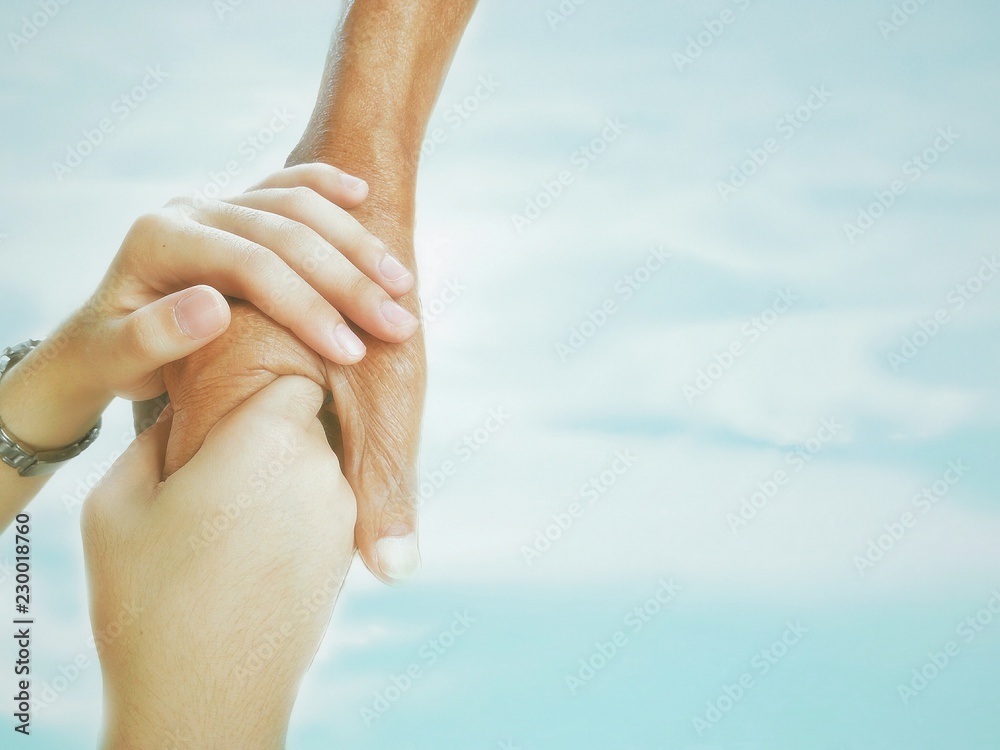 Soft image of young female hands are holding elderly male hand in morning physical therapy with blur cloud and blue sky background in attentive and encourage concept Soft image of young female hands are holding elderly male hand in morning physical therapy with blur cloud and blue sky background in attentive and encourage concept