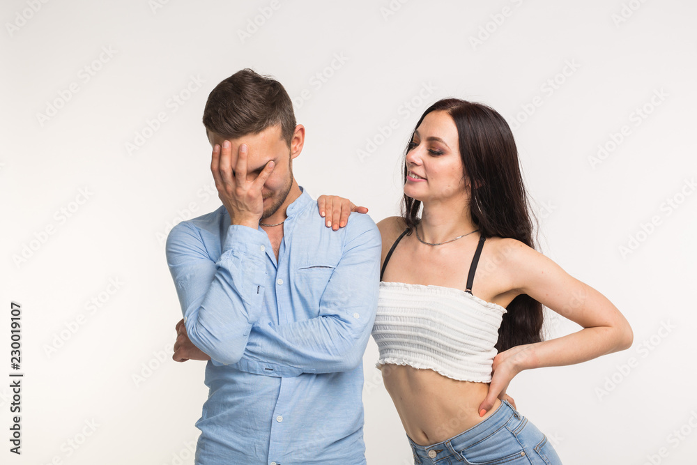 Emotions, relationship and people concept - funny young couple stand near to each over and man covered his face with his hand Emotions, relationship and people concept - funny young couple stand near to each over and man covered his face with his hand
