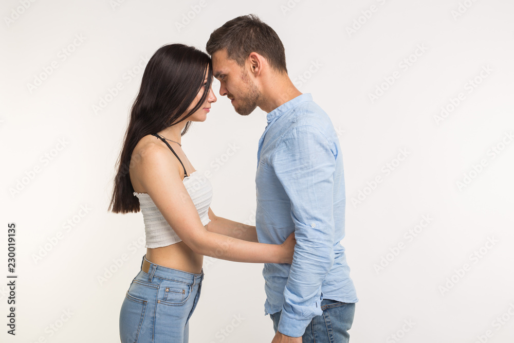 Relationship problems concept - Angry young woman hugging her husband on white background Relationship problems concept - Angry young woman hugging her husband on white background