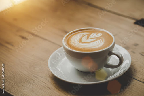 Hot of coffee cup cappuccino placed on a wooden floor in a cafe, warm toning, Beautiful foam on a white ceramic cup.