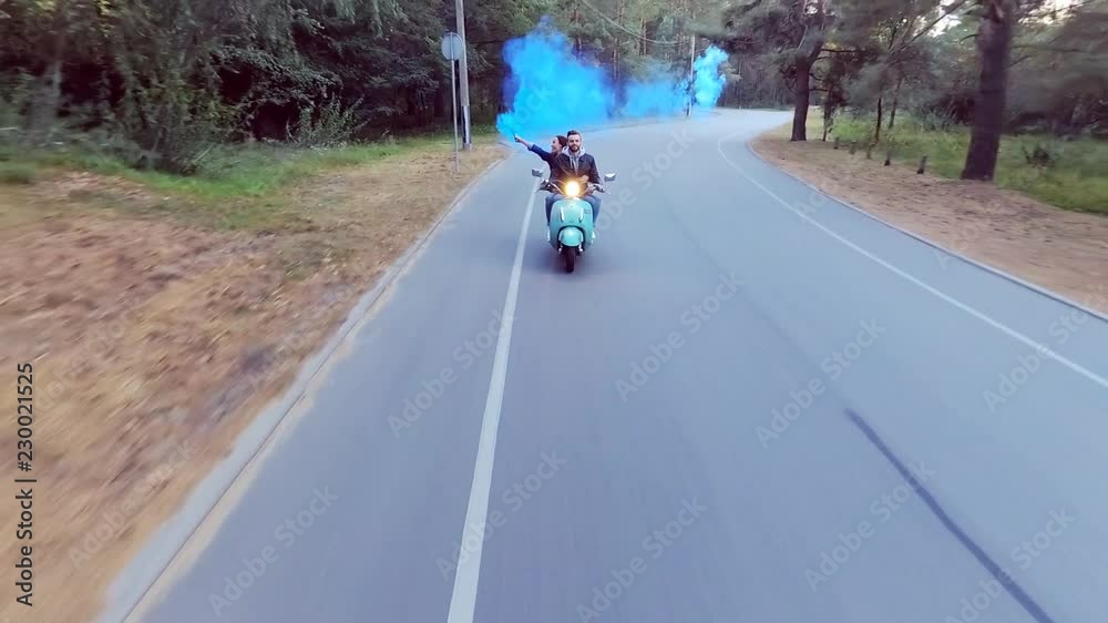 Couple riding a scooter. The girl in the hands holding the flare. Couple riding a scooter. The girl in the hands holding the flare.