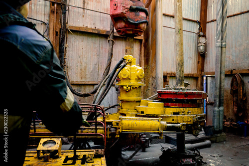 Offshore oil rig worker prepare tool and equipment for perforation oil and gas well at wellhead platform. Making up a drill pipe connection. A view for drill pipe connection from between the stands. photo