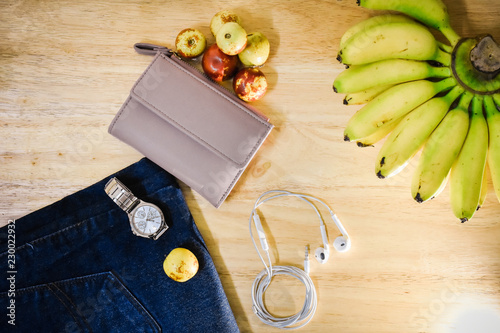 Watches and cashmere and fashion jeans are placed on the table.For travel to New Year,Banana and frute and jean and watch on wood background photo