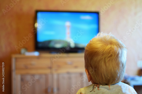 Canvastavla Three year old boy watching cartoons on TV blurred back view at shallow depth of field with focus on head