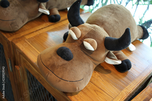 sleeping brown Buffalo doll, Peace calm bull with black horn on wooden table, background photo