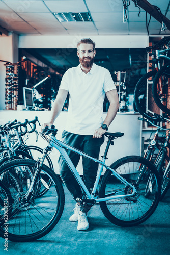 Smiling Salesman Poses near Bicycle in Sport Shop